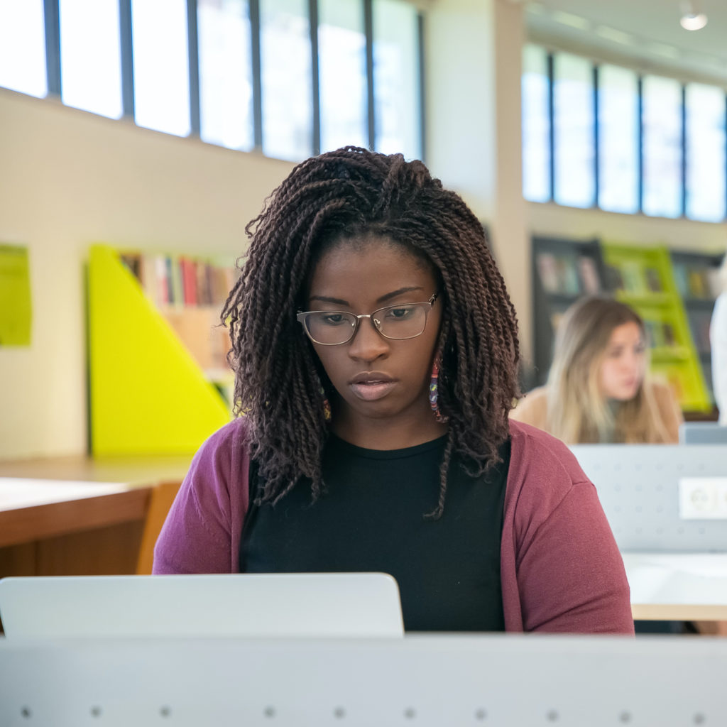 Young woman looking at computer at library