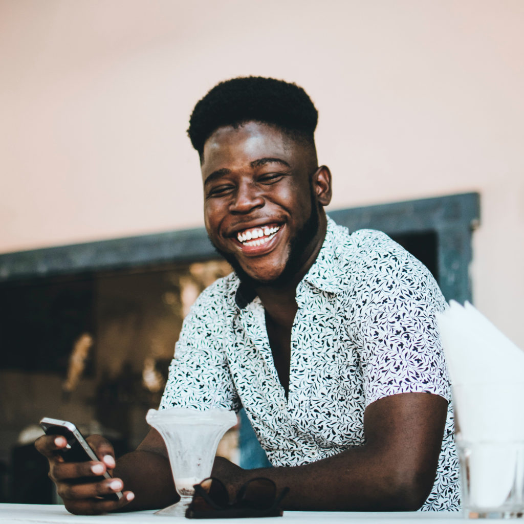 young man smiling holding his phone