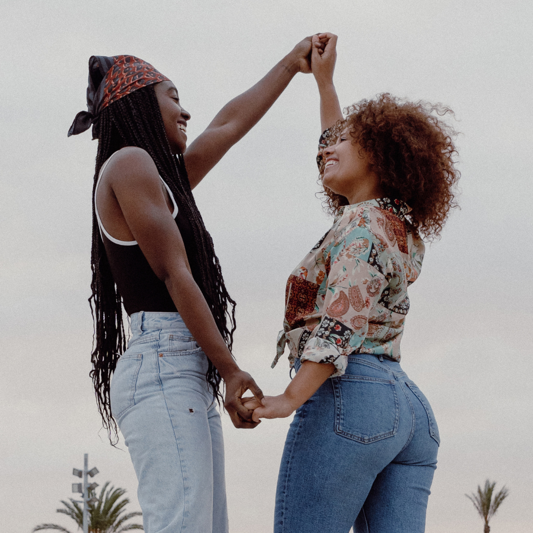 Two black women happily holding hands.